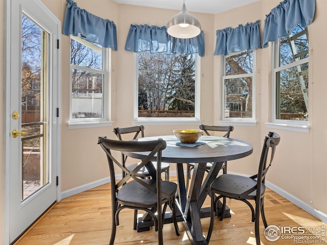 dining space with baseboards and light wood-style floors