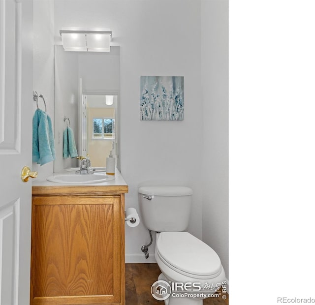 bathroom featuring baseboards, vanity, and toilet