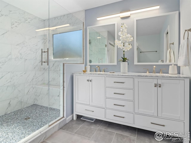 bathroom with double vanity, a marble finish shower, and a sink