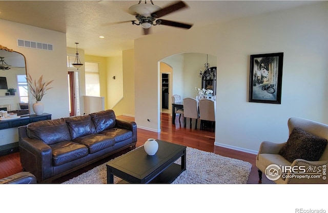 living area with visible vents, wood finished floors, arched walkways, baseboards, and ceiling fan