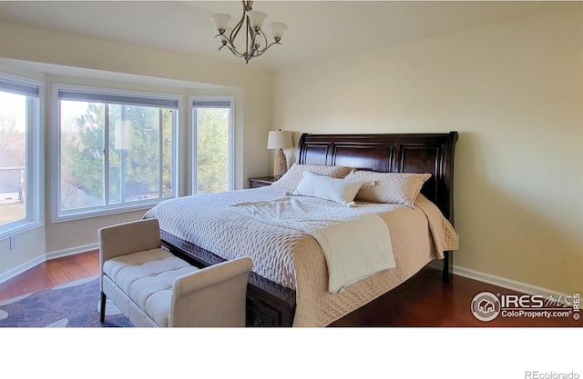 bedroom with baseboards, a notable chandelier, and wood finished floors