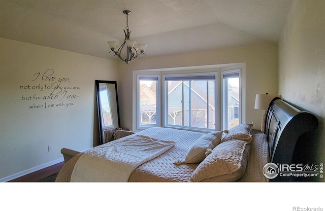 bedroom with a chandelier, lofted ceiling, and baseboards