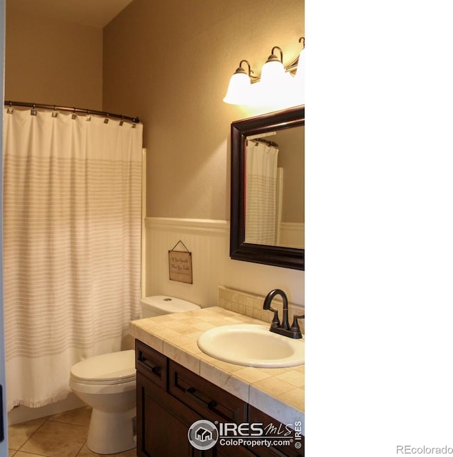 bathroom with vanity, a wainscoted wall, curtained shower, tile patterned floors, and toilet