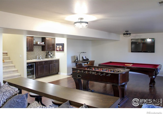 recreation room featuring a sink, wine cooler, light wood-style floors, indoor wet bar, and baseboards