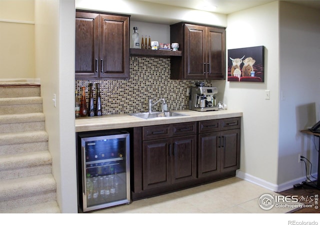 bar with beverage cooler, baseboards, a sink, decorative backsplash, and stairs