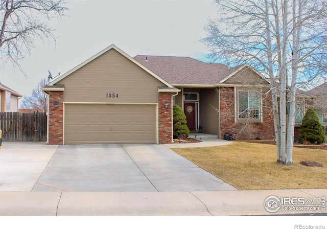 ranch-style house featuring a front yard, an attached garage, fence, and brick siding