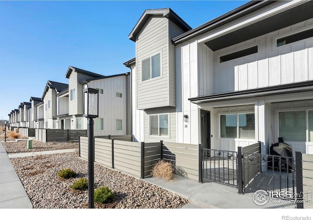 exterior space with a gate, fence, board and batten siding, and a residential view