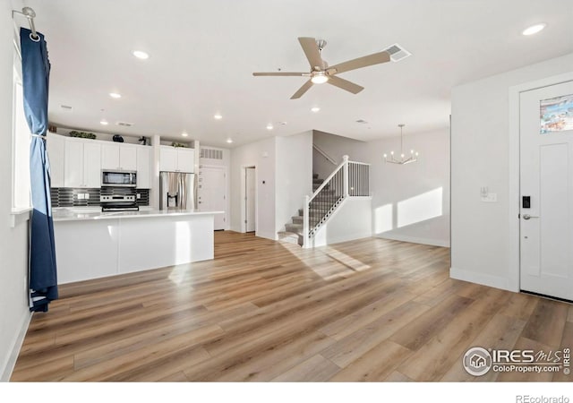 kitchen featuring white cabinetry, appliances with stainless steel finishes, open floor plan, and light wood finished floors