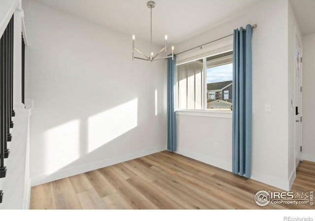 interior space with a notable chandelier, baseboards, and wood finished floors