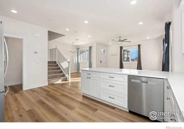 kitchen with light wood-style flooring, ceiling fan with notable chandelier, a peninsula, white cabinets, and dishwasher