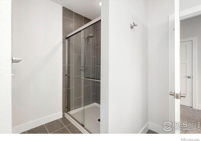 full bath featuring tile patterned floors, baseboards, and a stall shower