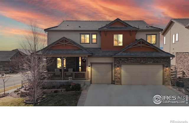 view of front of property featuring a porch, concrete driveway, stone siding, and a garage