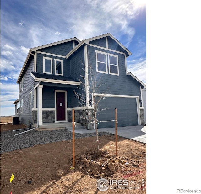 view of front facade with a garage, stone siding, driveway, and central AC