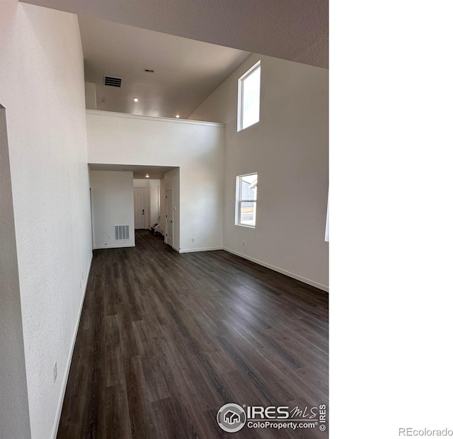 unfurnished living room with baseboards, visible vents, and dark wood-style flooring