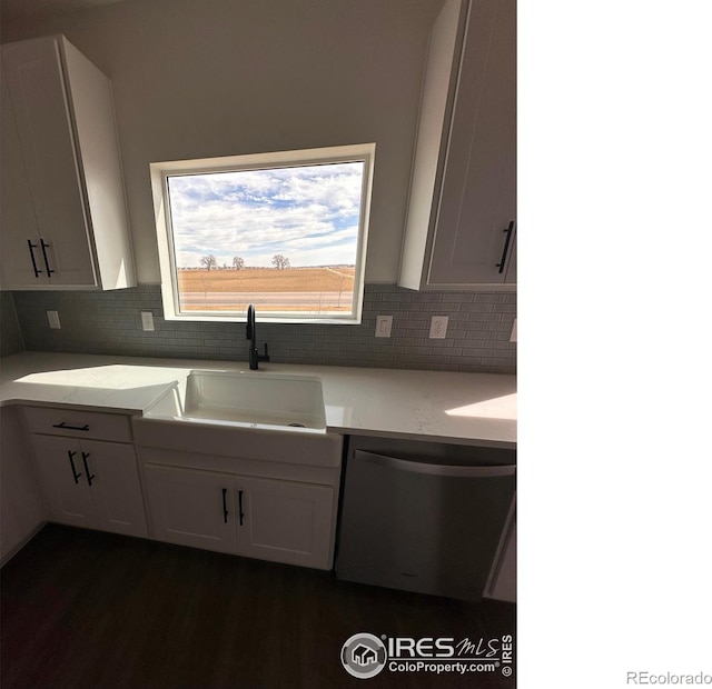 kitchen with tasteful backsplash, dishwasher, light stone counters, white cabinetry, and a sink