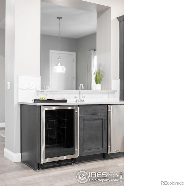 bar with light wood finished floors, wine cooler, a sink, and freestanding refrigerator