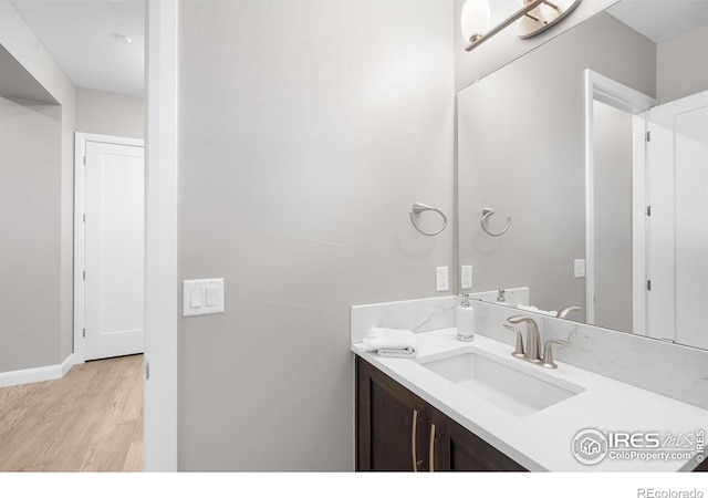 bathroom featuring baseboards, wood finished floors, and vanity