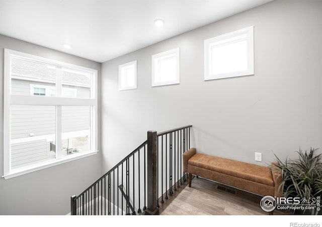 hall with recessed lighting, visible vents, an upstairs landing, and wood finished floors