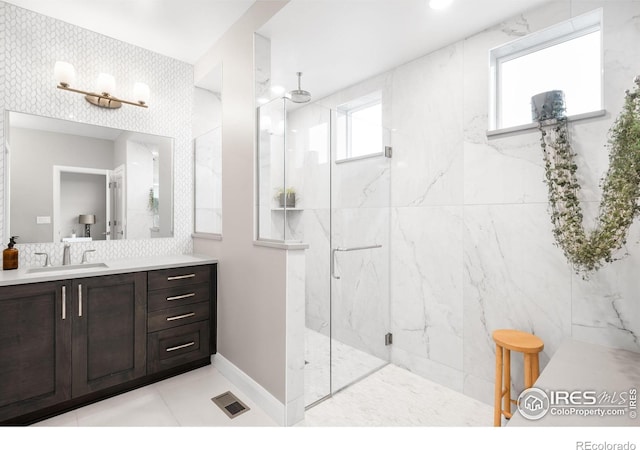 bathroom with visible vents, baseboards, vanity, and a marble finish shower