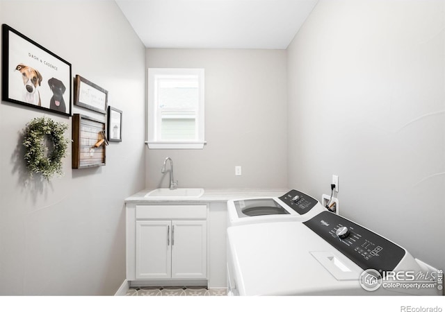 laundry area with cabinet space, washing machine and dryer, and a sink