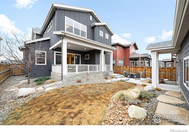 view of front of house with board and batten siding, a patio area, a porch, and fence