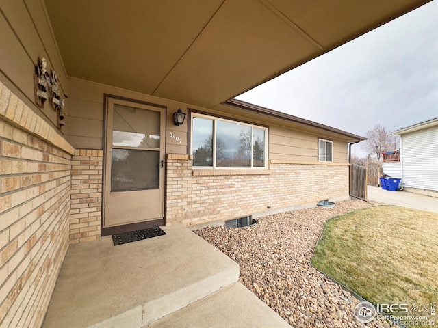 entrance to property featuring crawl space and brick siding