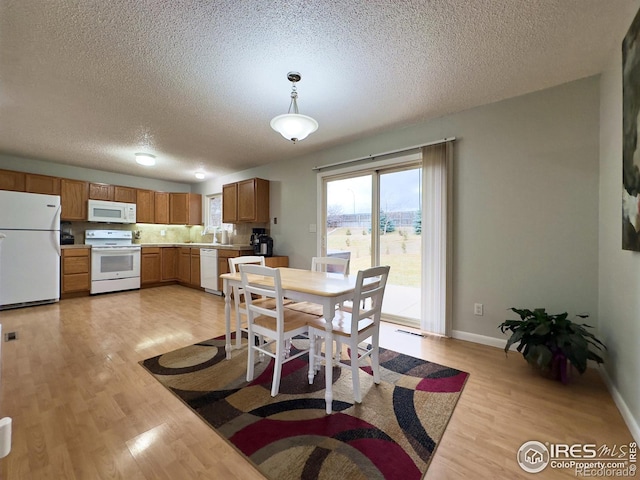 dining space with light wood-type flooring, baseboards, visible vents, and a textured ceiling