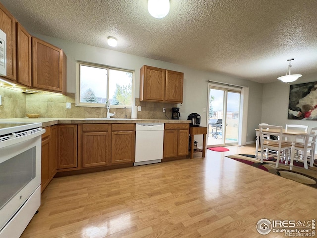 kitchen featuring light wood-style floors, white appliances, brown cabinets, and a sink