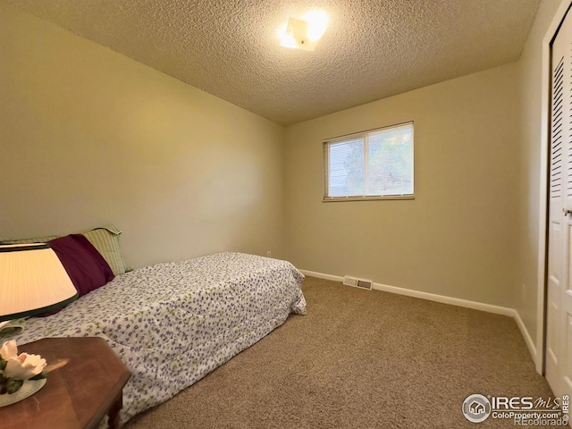 carpeted bedroom with a closet, visible vents, a textured ceiling, and baseboards