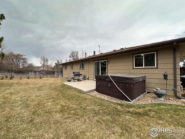 rear view of property with a patio area, a hot tub, fence, and a lawn