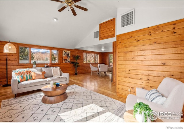 living room with a wealth of natural light, visible vents, and wooden walls