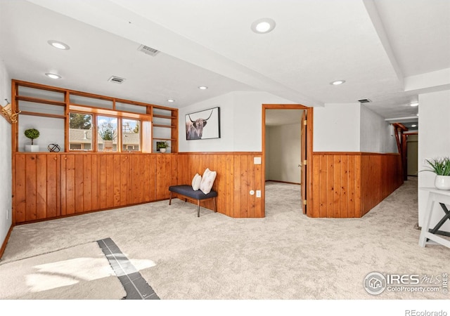 unfurnished room featuring a wainscoted wall, carpet, visible vents, and wood walls