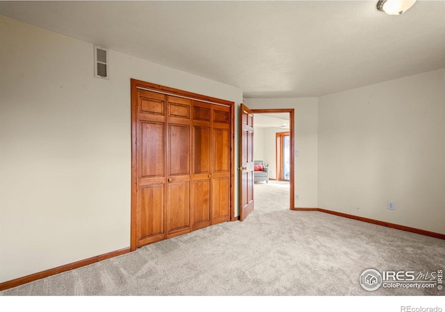 unfurnished bedroom with carpet, a closet, visible vents, and baseboards