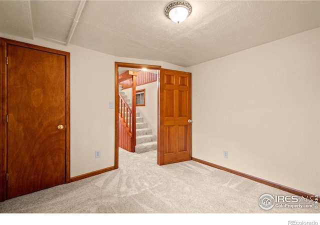 unfurnished bedroom featuring a textured ceiling, baseboards, and carpet flooring