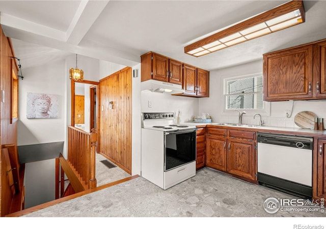 kitchen with under cabinet range hood, white appliances, a sink, light countertops, and brown cabinetry