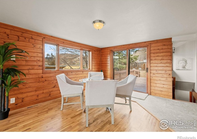 dining area with wood walls, wood finished floors, and visible vents