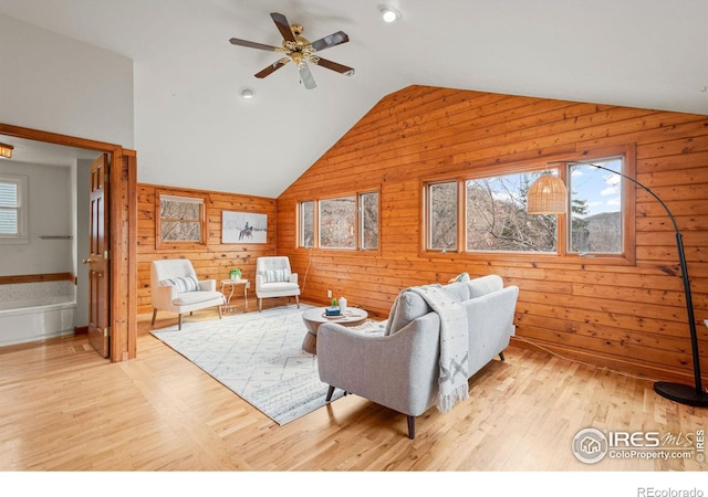 living room with light wood-style floors, a healthy amount of sunlight, vaulted ceiling, and ceiling fan