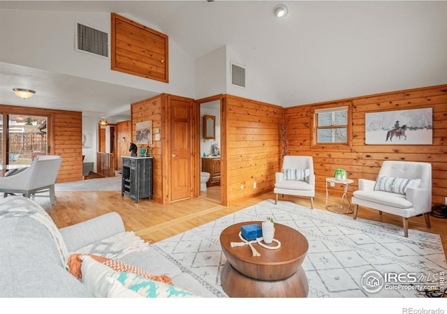 living room featuring wood walls, wood finished floors, and visible vents