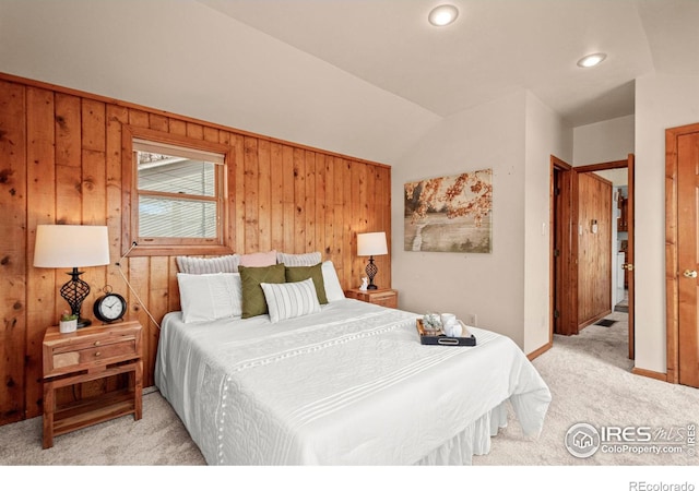 bedroom with light carpet, wood walls, baseboards, and lofted ceiling