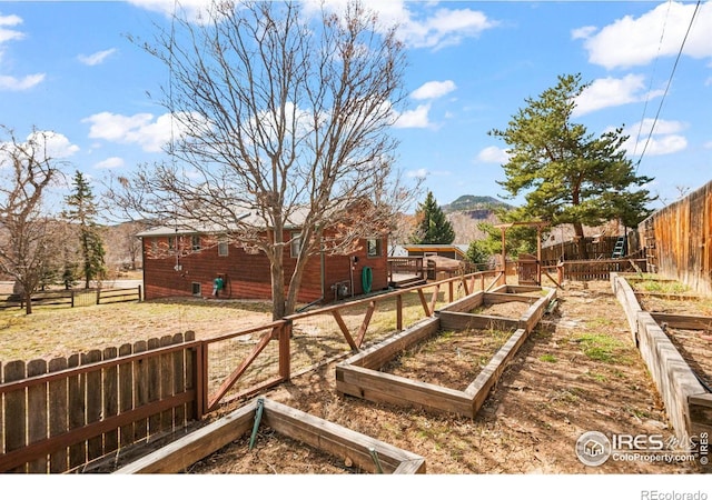 view of yard with a fenced backyard, a vegetable garden, and a mountain view