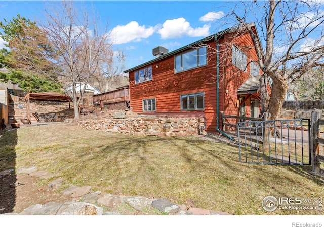 back of property with central air condition unit, fence, and a yard