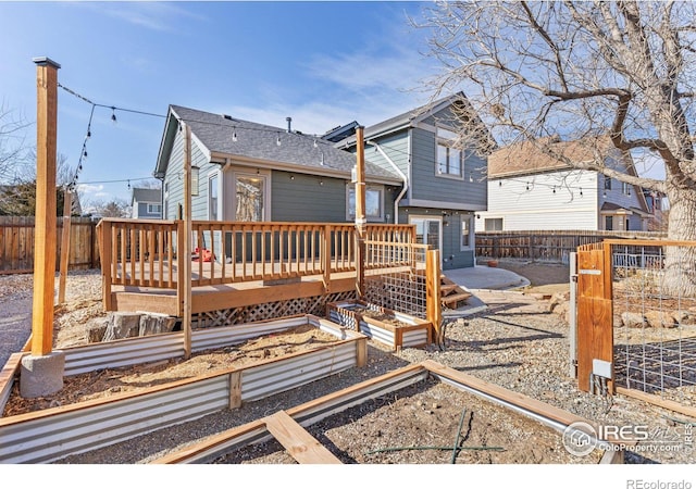 back of property with a garden, a deck, and a fenced backyard