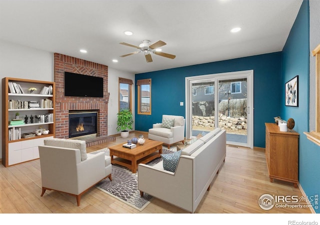 living room featuring recessed lighting, a ceiling fan, a brick fireplace, light wood-type flooring, and baseboards