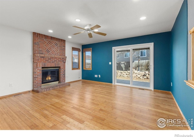 unfurnished living room with ceiling fan, recessed lighting, wood finished floors, baseboards, and a brick fireplace