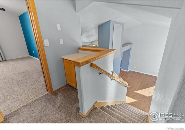 stairway with carpet flooring, vaulted ceiling, and baseboards