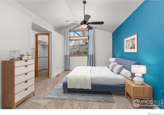 bedroom featuring a textured wall, carpet, vaulted ceiling, and ceiling fan