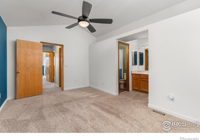 unfurnished bedroom featuring connected bathroom, light carpet, visible vents, baseboards, and vaulted ceiling