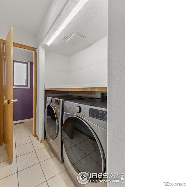 washroom with light tile patterned floors, laundry area, and washing machine and clothes dryer