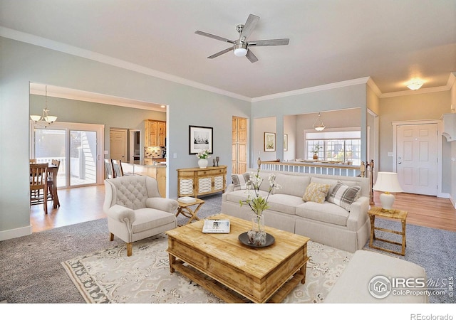 living area featuring ceiling fan with notable chandelier, ornamental molding, baseboards, and light wood-style floors