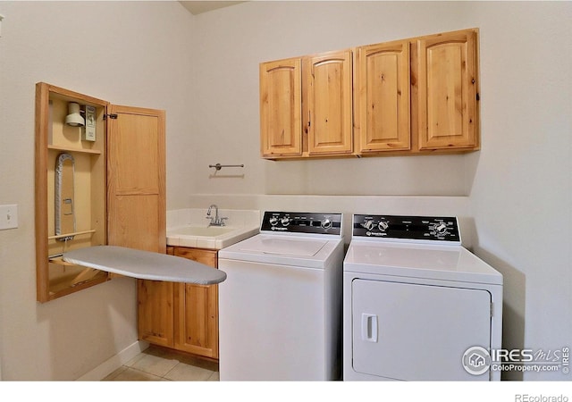 washroom with light tile patterned flooring, independent washer and dryer, a sink, and cabinet space